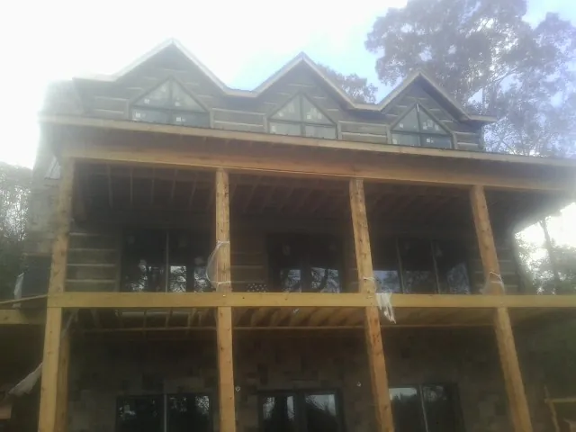Dormers and porch framing on a large log home under construction — Roof Coating work by our crew in Cobb