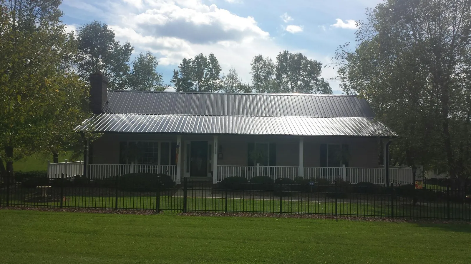 Gray metal roof on a brick ranch with a full width front porch — Gutter Guard Installation work by our crew in Cobb